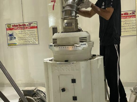 Rice mill staff operating processing machinery